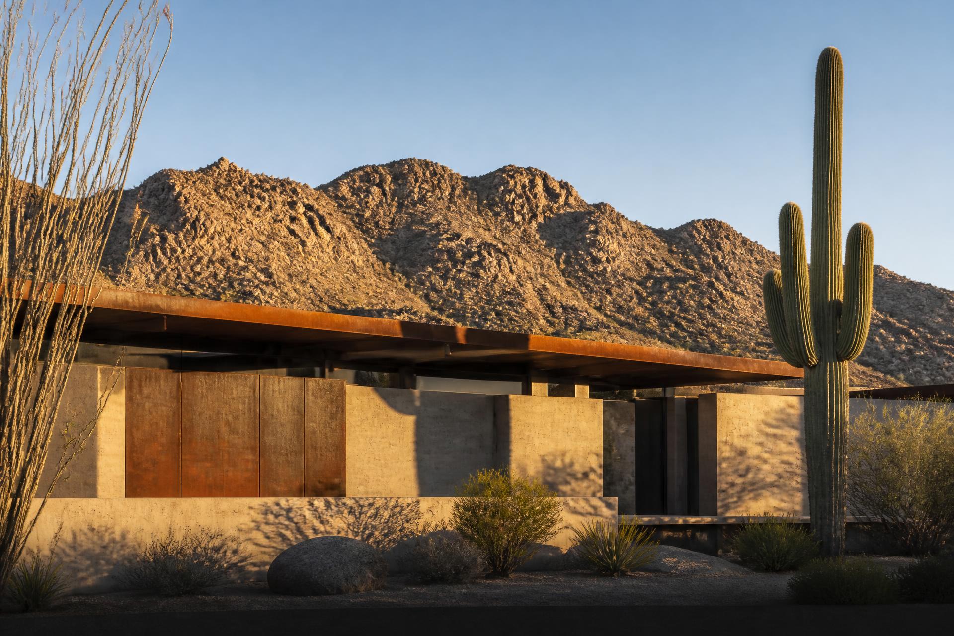 A long horizontal facade of a Scottsdale desert residence in raking morning light against the McDowell ridgeline
